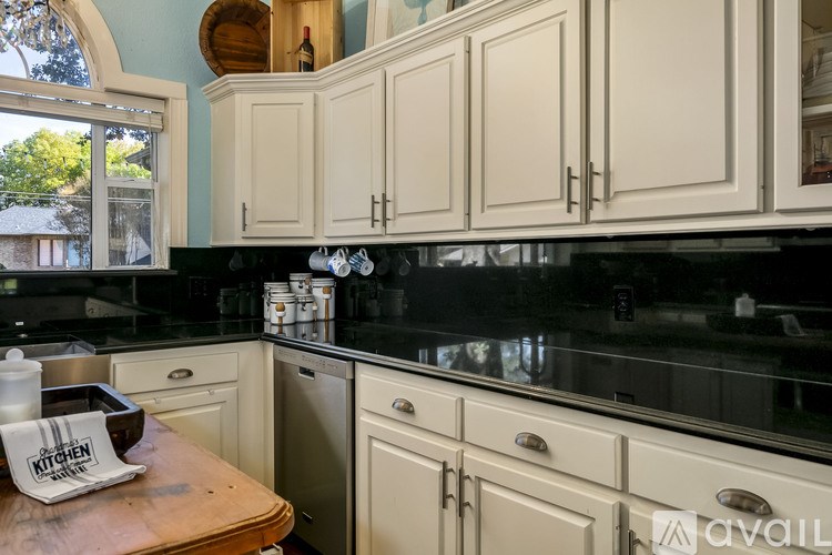 A kitchen with white cabinets and a black countertop.