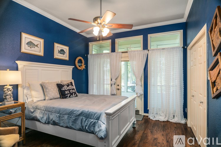 A bedroom with a bed, a ceiling fan, and a window with curtains.