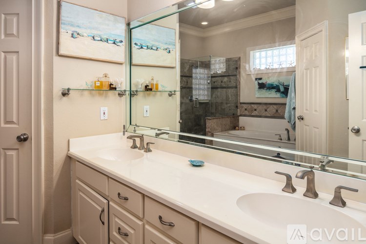A bathroom with a large mirror above a sink with two faucets.