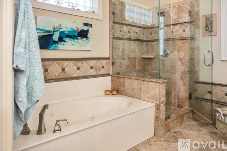 A bathroom with a tub, shower, and a painting of a boat on the wall.