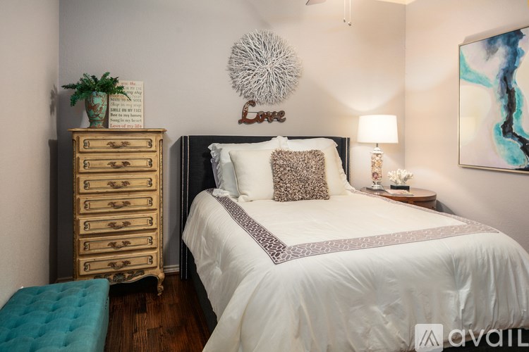 A bedroom with a large bed, a wooden chest of drawers, and a painting on the wall.