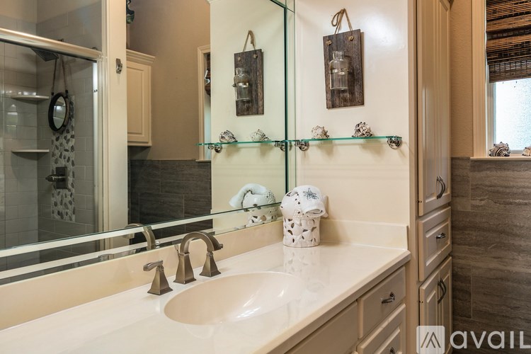 A bathroom with a sink, mirror, and a shower.