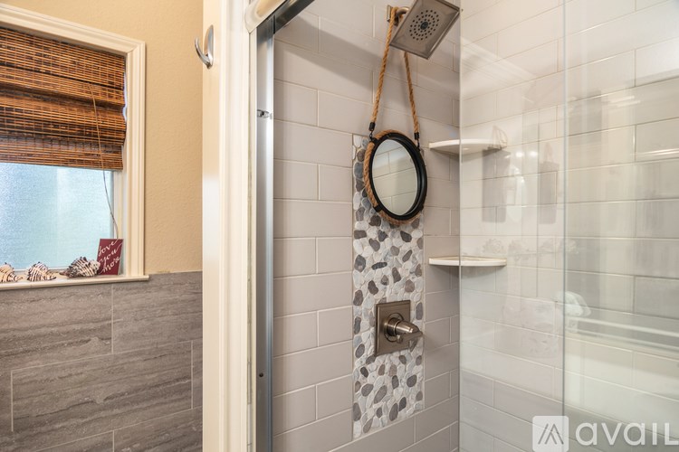 A bathroom with a shower and a mirror on the wall.