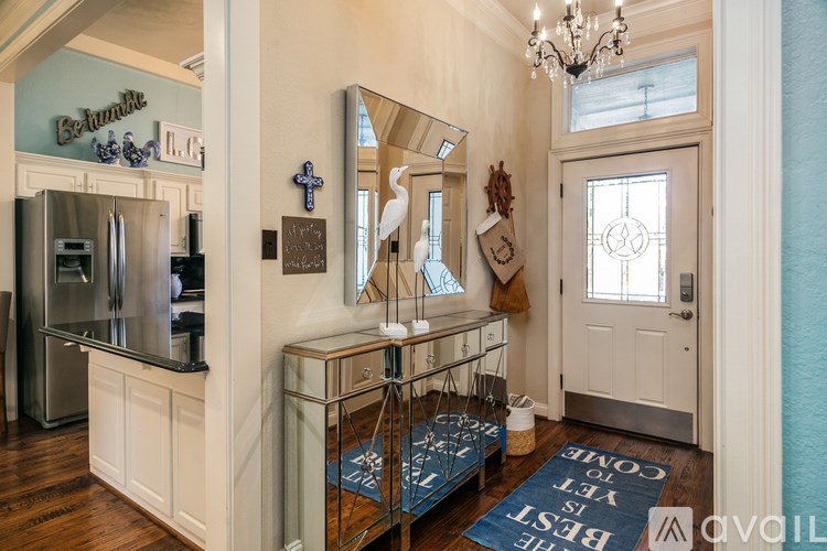 A kitchen with a refrigerator, a mirror, and a chandelier.