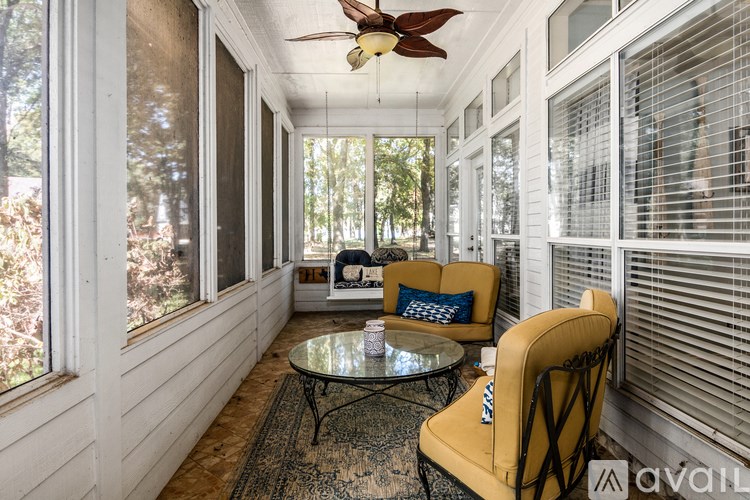 A sunny room with a yellow chair and a glass table.
