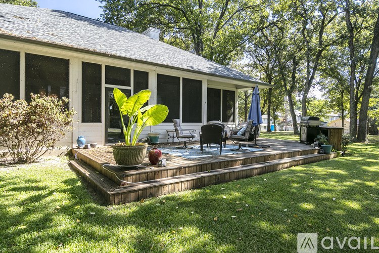 A sunny day at a house with a deck and patio furniture.