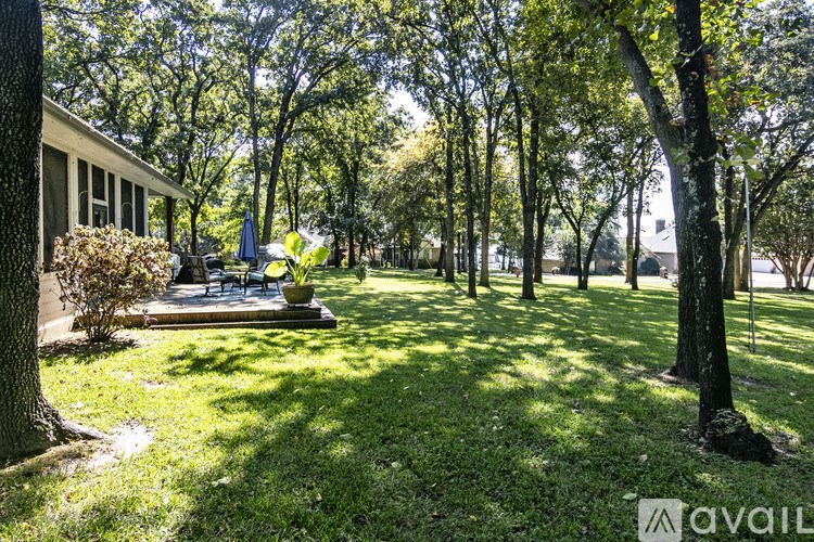A sunny day in a park with a house and trees.