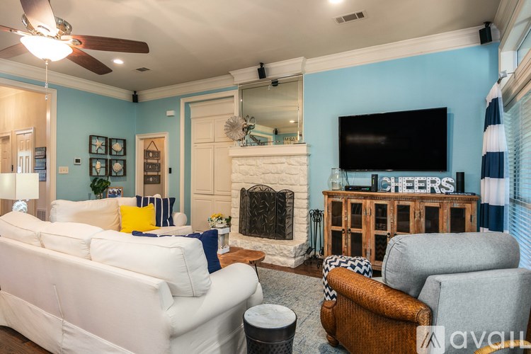 A living room with a white couch, a fireplace, and a TV on the wall.