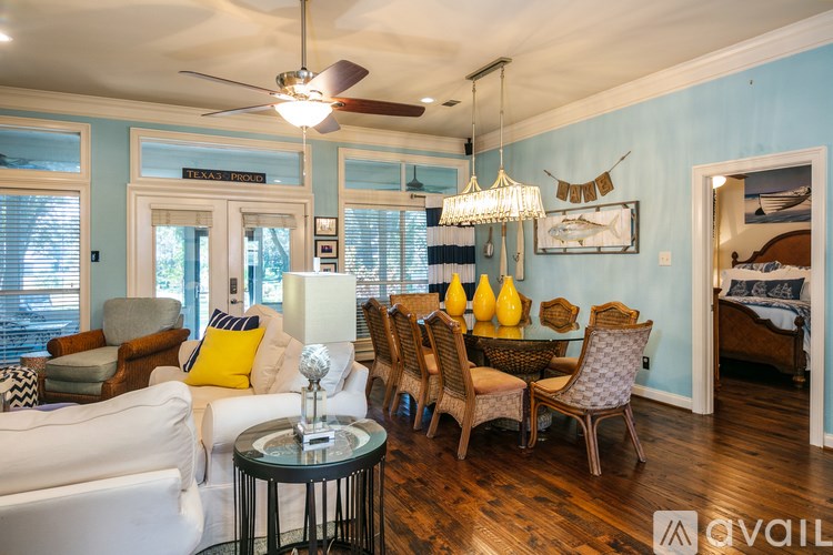 A living room with a white couch, a glass table, and a chandelier.
