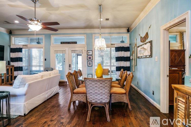 A living room with a white couch and a dining table with chairs.