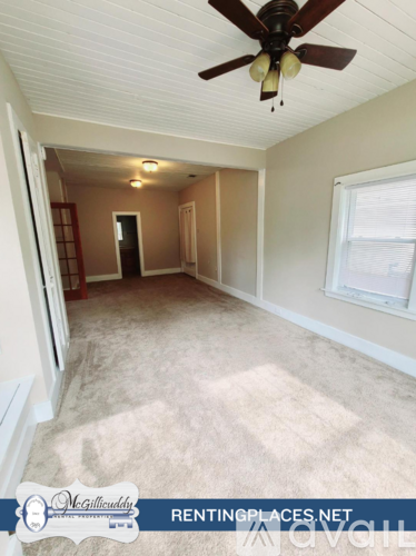 A room with beige carpeting and a window with blinds.