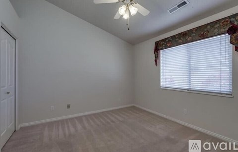 A room with a ceiling fan and a window with blinds.