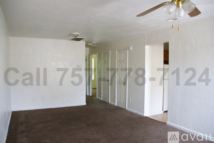 A room with a carpeted floor and a ceiling fan.