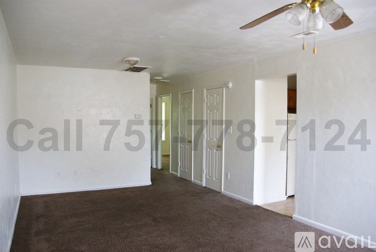 A room with a carpeted floor and a ceiling fan.