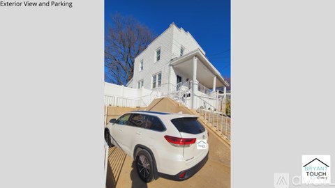 A white car is parked in front of a white building with a clear blue sky in the background.