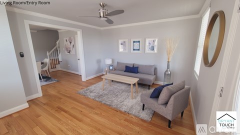 A living room with a grey couch and a grey rug.