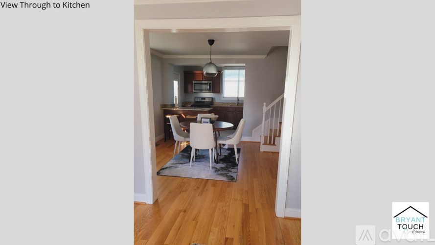A kitchen with a dining table and chairs is visible through a doorway.