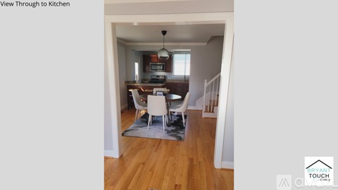 A kitchen with a dining table and chairs is visible through a doorway.