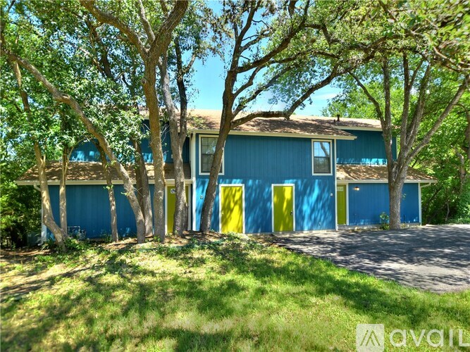 A blue house with yellow doors surrounded by trees.