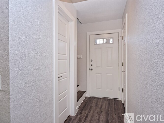 A white door is in a hallway with a wooden floor.