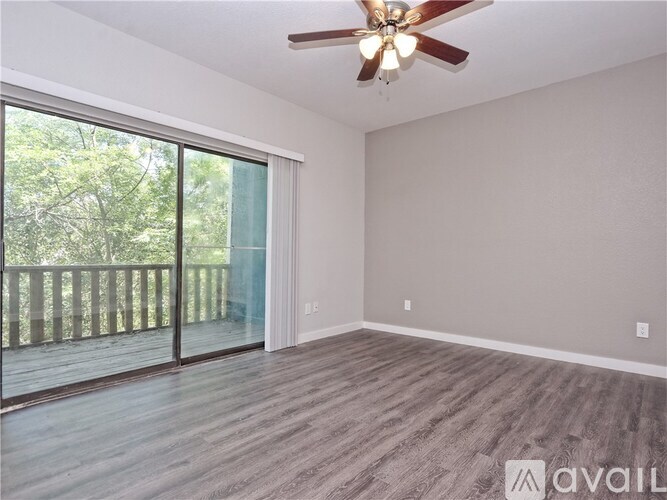 A room with a ceiling fan and sliding glass doors leading to a deck.