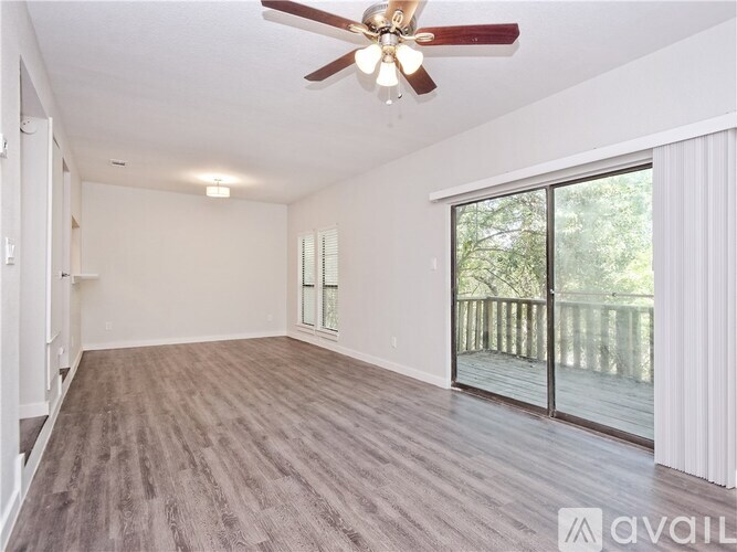 A spacious room with a ceiling fan and sliding glass doors leading to a deck.