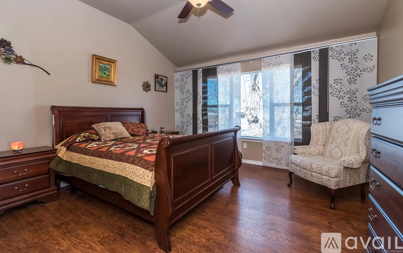 A bedroom with a bed, chair, and a ceiling fan.