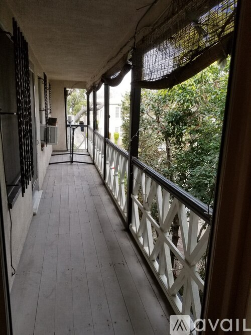 A balcony with a white railing and a view of trees.