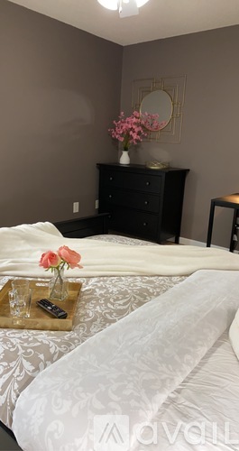A bedroom with a bed, nightstand, and a dresser with a mirror.