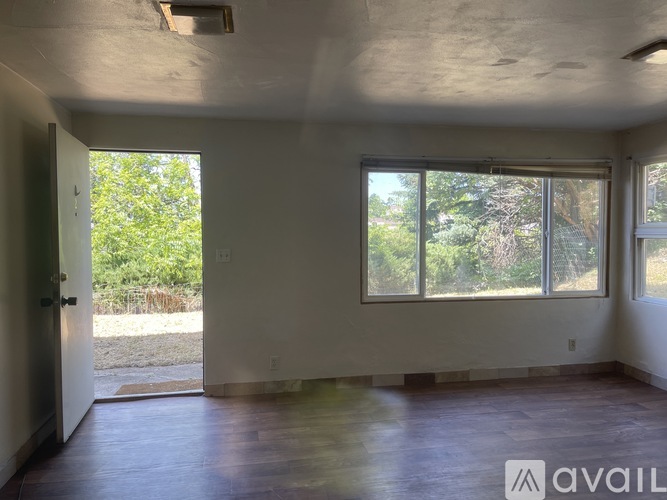 A room with a door and a window with a view of trees.