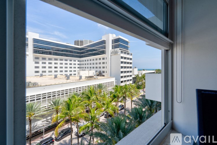 A view from a window looking out at a cityscape with palm trees.