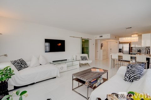 A living room with a white couch and a television on the wall.