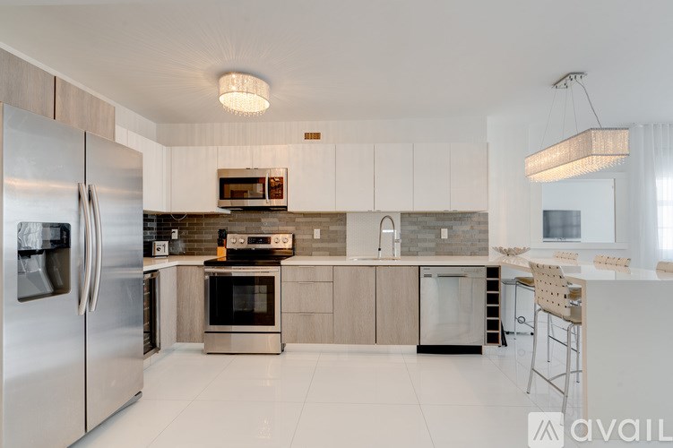 A modern kitchen with a refrigerator, oven, and bar stools.