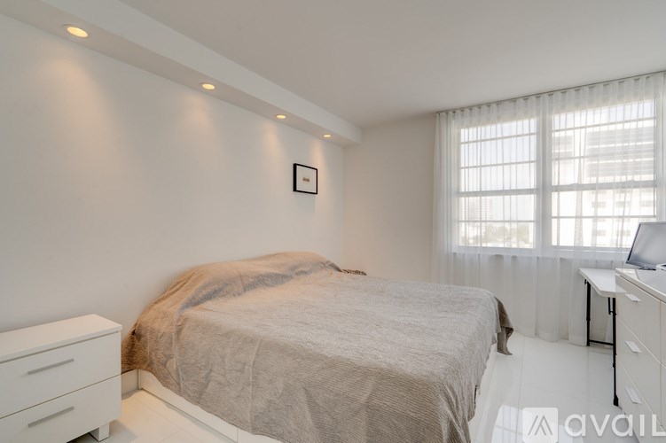 A bedroom with a bed, dresser, and window.
