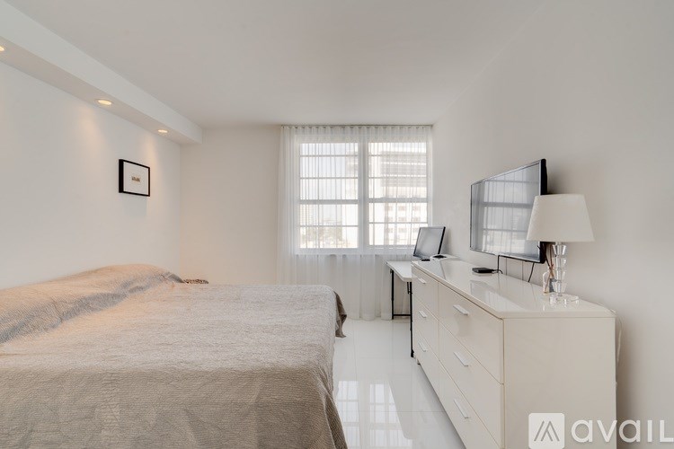 A bedroom with a bed, desk, and window.