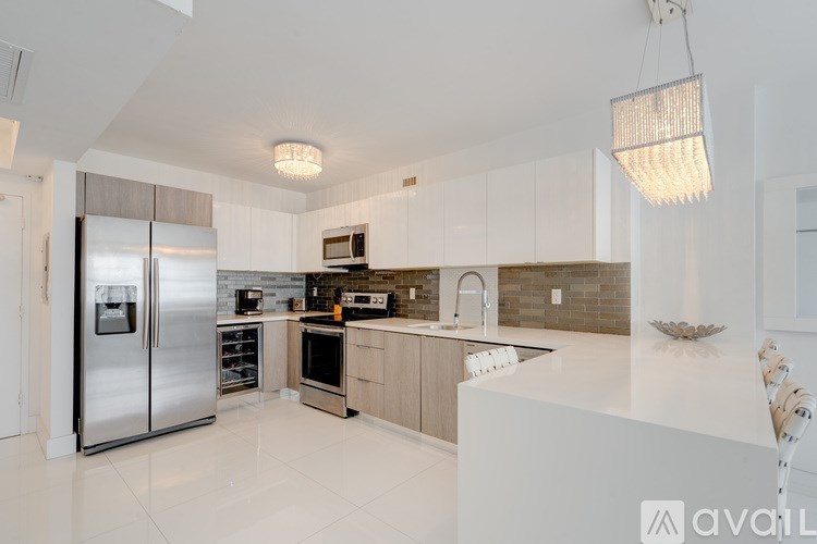A modern kitchen with a stainless steel refrigerator and a white countertop.