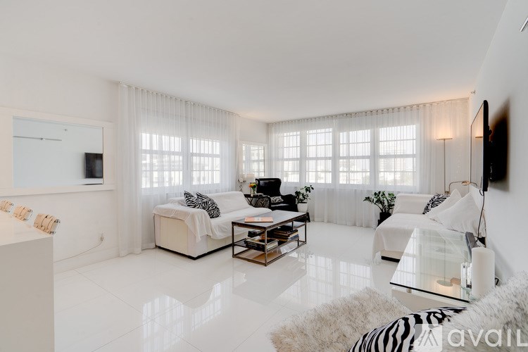 A modern living room with white furniture and a zebra print rug.