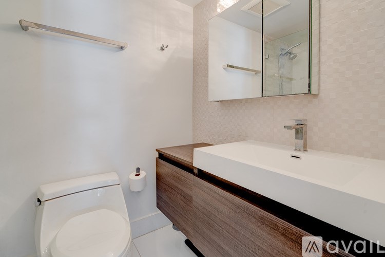 A white toilet sits next to a wooden vanity with a mirror above it.