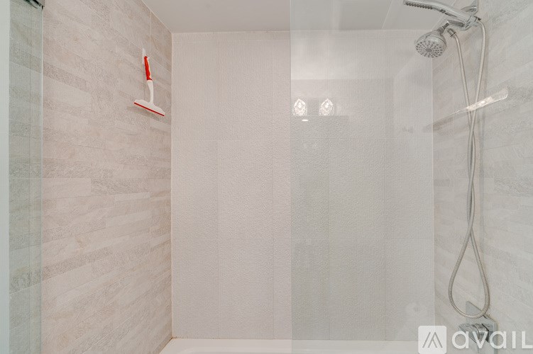 A shower area with a glass door and a red shower head.