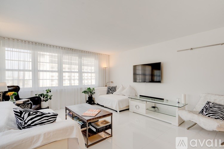 A living room with a white couch, a coffee table, and a television.