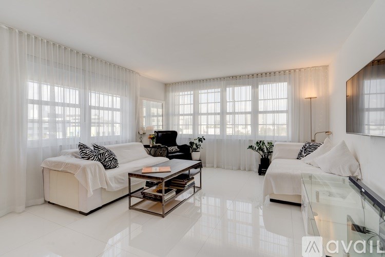 A living room with white furniture and a glass table.