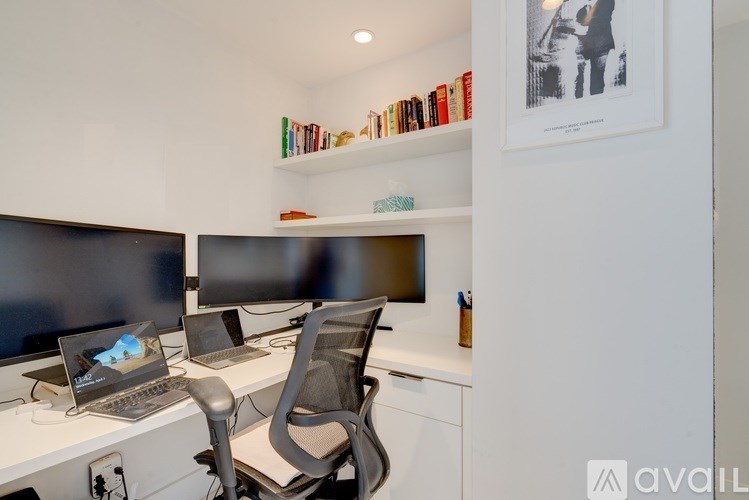 A modern home office with two monitors, a laptop, and a chair.