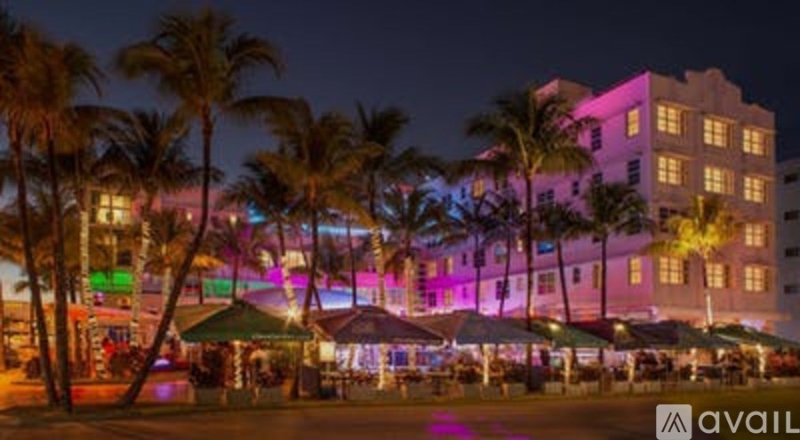 A hotel with palm trees in front of it at night.