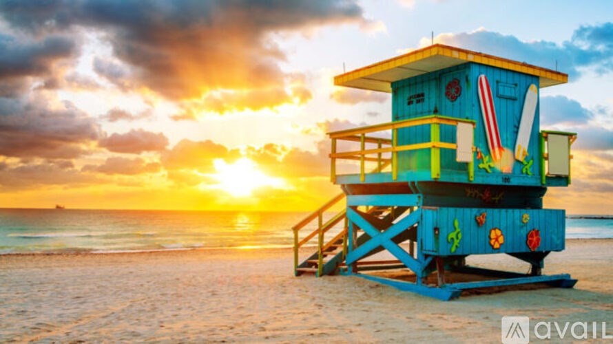 A lifeguard tower on a beach with a sunset in the background.