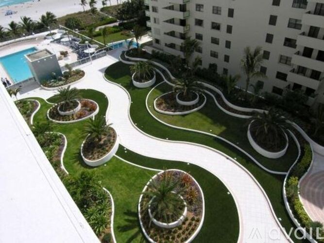 A white building with a pool and a green lawn with a white fence.