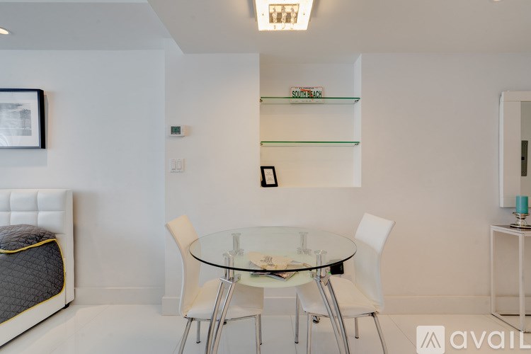 A modern dining room with a glass table and white chairs.