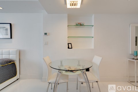 A modern dining room with a glass table and white chairs.