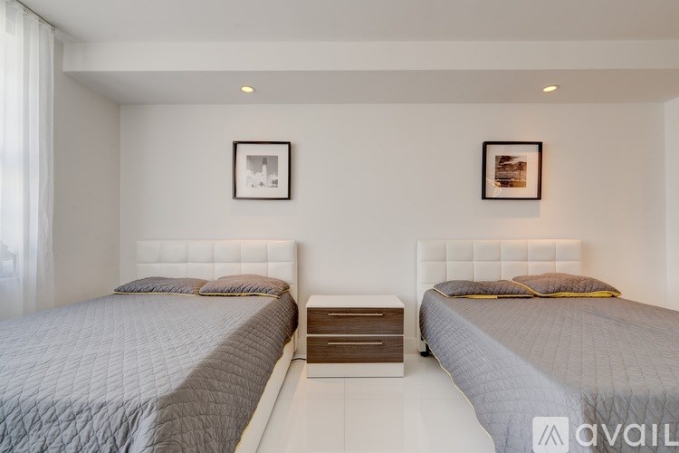 Two twin beds with white headboards and a nightstand in between them.