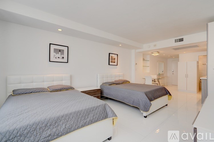 Two beds in a white bedroom with a picture on the wall.