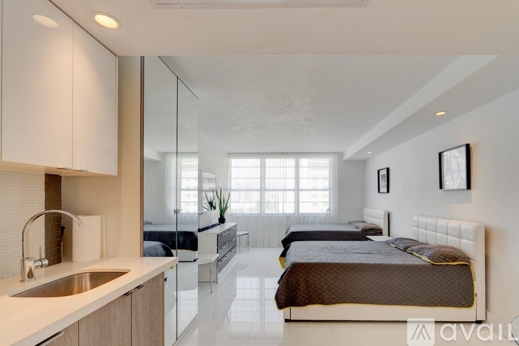 A modern bedroom with a large bed and a kitchen area.